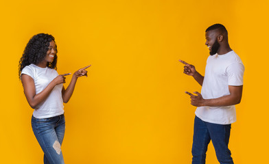 African american man and woman pointing at empty space