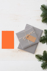 Stylishly packaged gifts with a tag and tied with a craft rope. Top view of the beautiful gifts for Christmas and New Year. Blank orange greeting card for text. Holiday season and winter concept