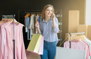 Pretty shopper with bags talking on smartphone