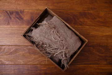 An old brown wooden box with old burlap on dark wooden background.  Shabby chic or rustic style. storage system