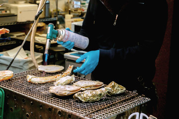 Seafood Chef using burner cooking king crab lags and oyster on stove for customer at seafood street market.