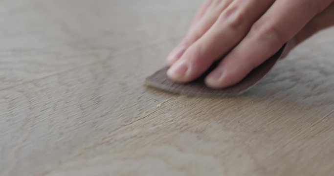 Slow motion closeup man hand sandig oak surface with sanding pad
