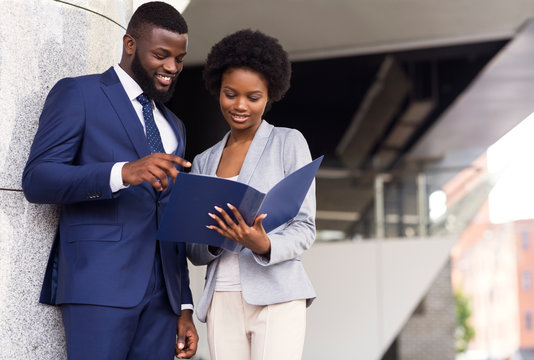 Successful business partners checking financial reports outdoors