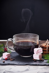 Coffee with milk preparation in glass cup on black background with coffee beans and sugar