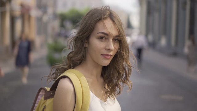 Close up portrait of Young Brunette Woman with cute freckles at sunset, Girl wearing white blause. Slow motion.