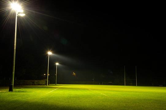 Foto Stock Green rugby field and goal posts with spotlight at night time,  Rugby is the most popular sport in New Zealand. | Adobe Stock