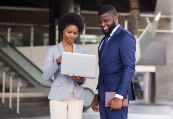 Young woman pointing finger to laptop screen while standing outdoors