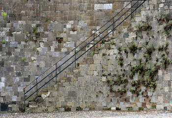 Stairs and iron railing along a stone wall