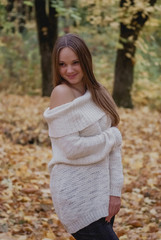 Close up portrait of a Beautiful girl in white sweater near colorful autumn leaves. Artwork of romantic woman .Pretty tenderness model smiling