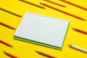 back to school. stationery colored pencils and notebook on a bright yellow background.