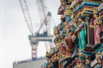 Fototapeta na wymiar Sri Mahamariamman Temple ornaments of structure in contrast to construction cranes in background in Kuala Lumpur