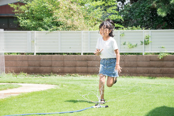 庭で水遊びをする女の子