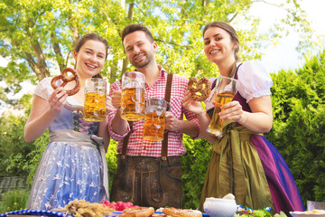 Young people in Tracht, Dindl and Lederhosen having fun in Beer garden