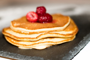 Pancakes with raspberries on black slate plate