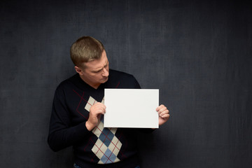 Portrait of focused man holding white blank paper sheet