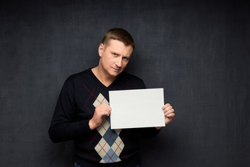 Portrait of focused man holding white blank paper sheet