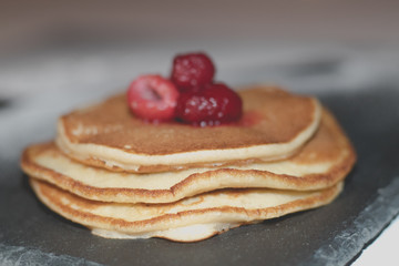 Pancakes with raspberries on black slate plate
