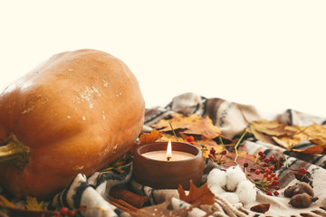 Hygge lifestyle, autumn mood. Pumpkin and candle with berries, fall leaves, anise,herbs, acorns, nuts, cinnamon, cotton on brown blanket. Happy Thanksgiving. Cozy inspirational image