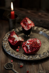 Pomegranate peeled on a silver plate, on a dark wooden table.