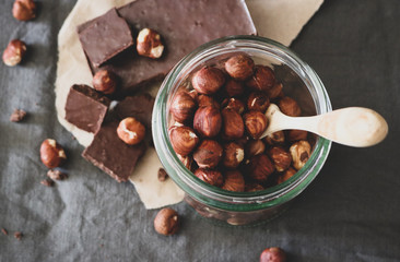 Dark chocolate and hazelnuts in a jar on a grey tablecloth background
