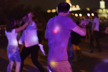 Photography of dancing people on the night party in the city street in  summer night.  Leisure, happiness and entertainment theme.
