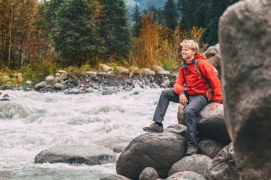 Young man tourist sits  rocky mountain river bank