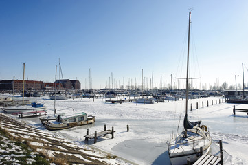 Frozen water and show on sea and boats in harbor at sunny winter day in Hoorn city, Holland Kroon,...