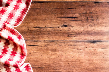 Checkered red napkin on an old wooden brown background, top view. Image with copy space. Kitchen table with a towel - top view with copy space. 
