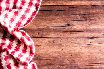 Checkered red napkin on an old wooden brown background, top view. Image with copy space. Kitchen table with a towel - top view with copy space. 