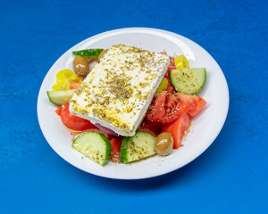 fresh Greek salad plate on vibrant blue table background