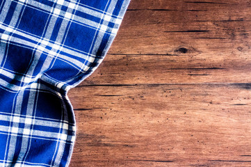 Checkered blue napkin on an old wooden brown background, top view. Image with copy space. Kitchen table with a towel - top view with copy space. 