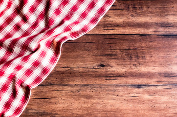 Checkered red napkin on an old wooden brown background, top view. Image with copy space. Kitchen table with a towel - top view with copy space. 