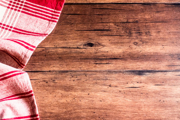 Striped red and white napkin on an old wooden brown background, top view. Image with copy space. Kitchen table with a towel - top view with copy space. 