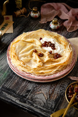 Homemade stack of thin crepes with sour cream and red jam on vintage pink plates