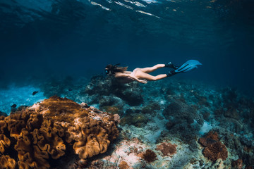 Fototapeta na wymiar Freediver woman with fins glides over coral bottom in underwater