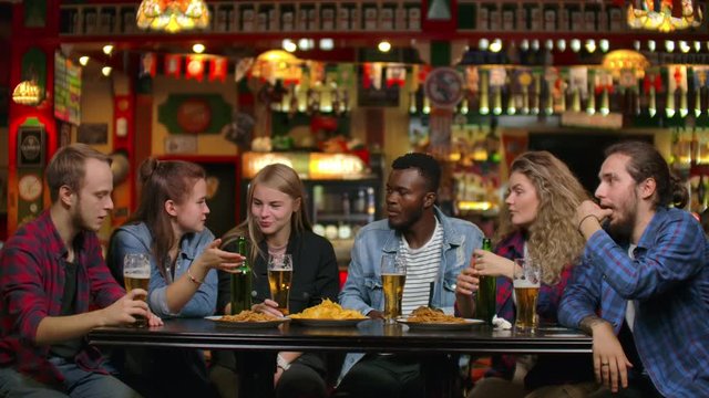 African American with friends at a bar drinking beer and eating chips with friends