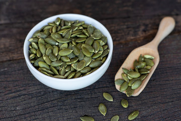 Pumpkin grain in wooden bowl and fresh pumpkin fruit on classic wooden table background, cereal