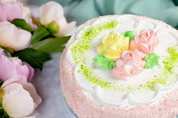 Obraz na płótnie Canvas Beautiful delicious cake decorated with flowers in pastel colors on wooden table with peonies, top view