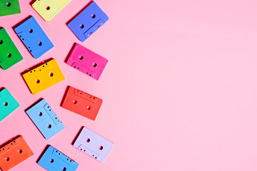 Painted audio cassettes on pastel pink background, copy space, top view. Retro musical background