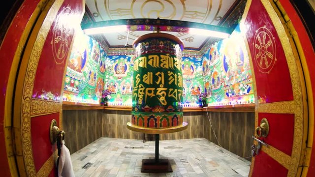 Beautiful huge bhuddhist prayer wheel in an ornately decorated room shot with a fisheye lens