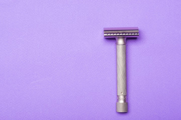 Metallic safety razor on purple background 