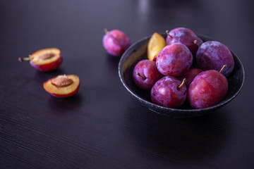 Fresh delicious plums in a plate on a black background