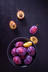 Fresh delicious plums in a plate on a black background