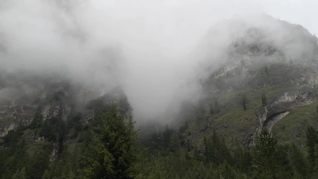 Mountains engulfed in fog and clouds on a rainy day in Vallunga valley, Selva, South Tyrol, Italy.