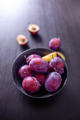 Delicious juicy blue plums in a bowl on the table,
