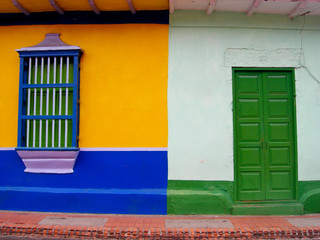 Blue and yellow wall with green windows and light blue wall with green door