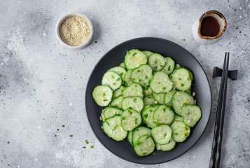 Asian salad with fresh cucumbers, sesame seeds and herbs on a light background