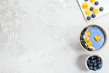 Blue matcha smoothies with berries and fruits in a bowl on a gray.