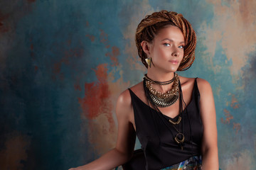 Southern spices. A beautiful young blue-eyed woman with afrocos and large ornaments against...