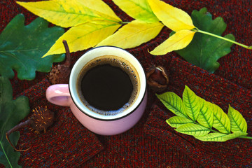 Autumn coffee. Fall leaves with a cup of hot healthy drink, warm wool sweater on a brown wooden background. Still life.